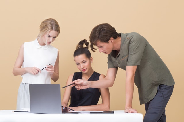 three advertising specialists looking at a laptop analyzing an ad